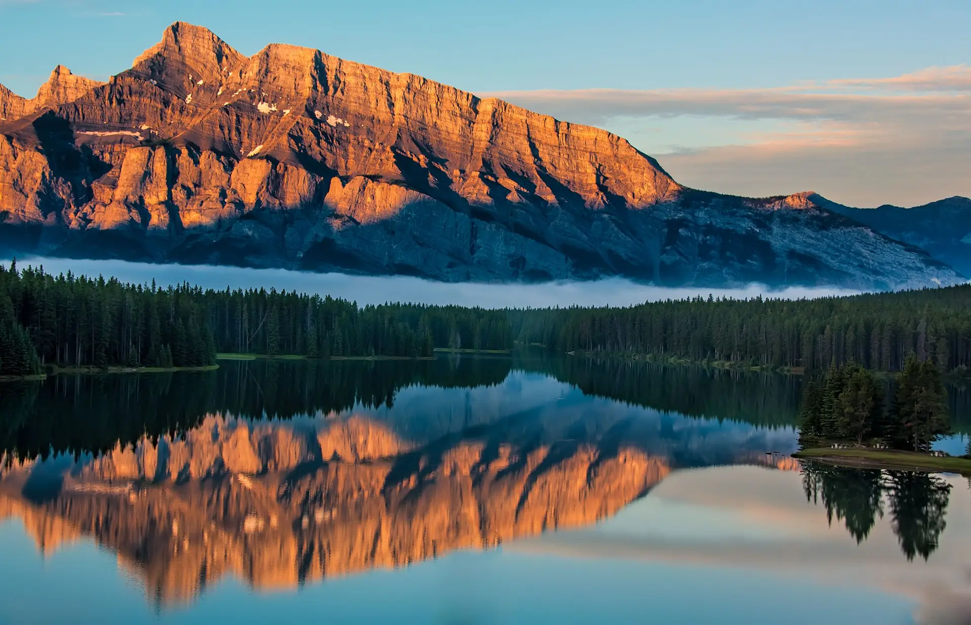 Capture of a serene Canadian lake reflecting majestic mountains at sunrise in the wilderness