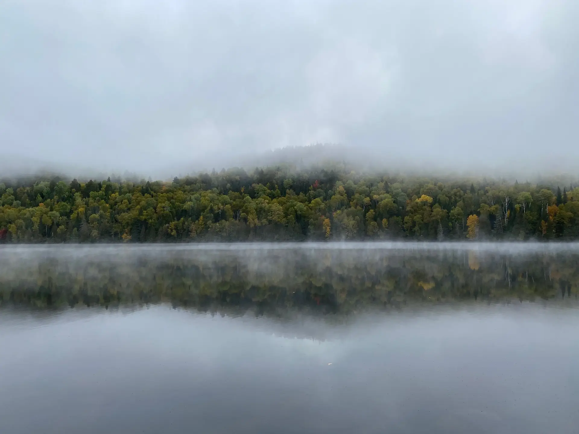 Morning mist rising over calm Canadian lake