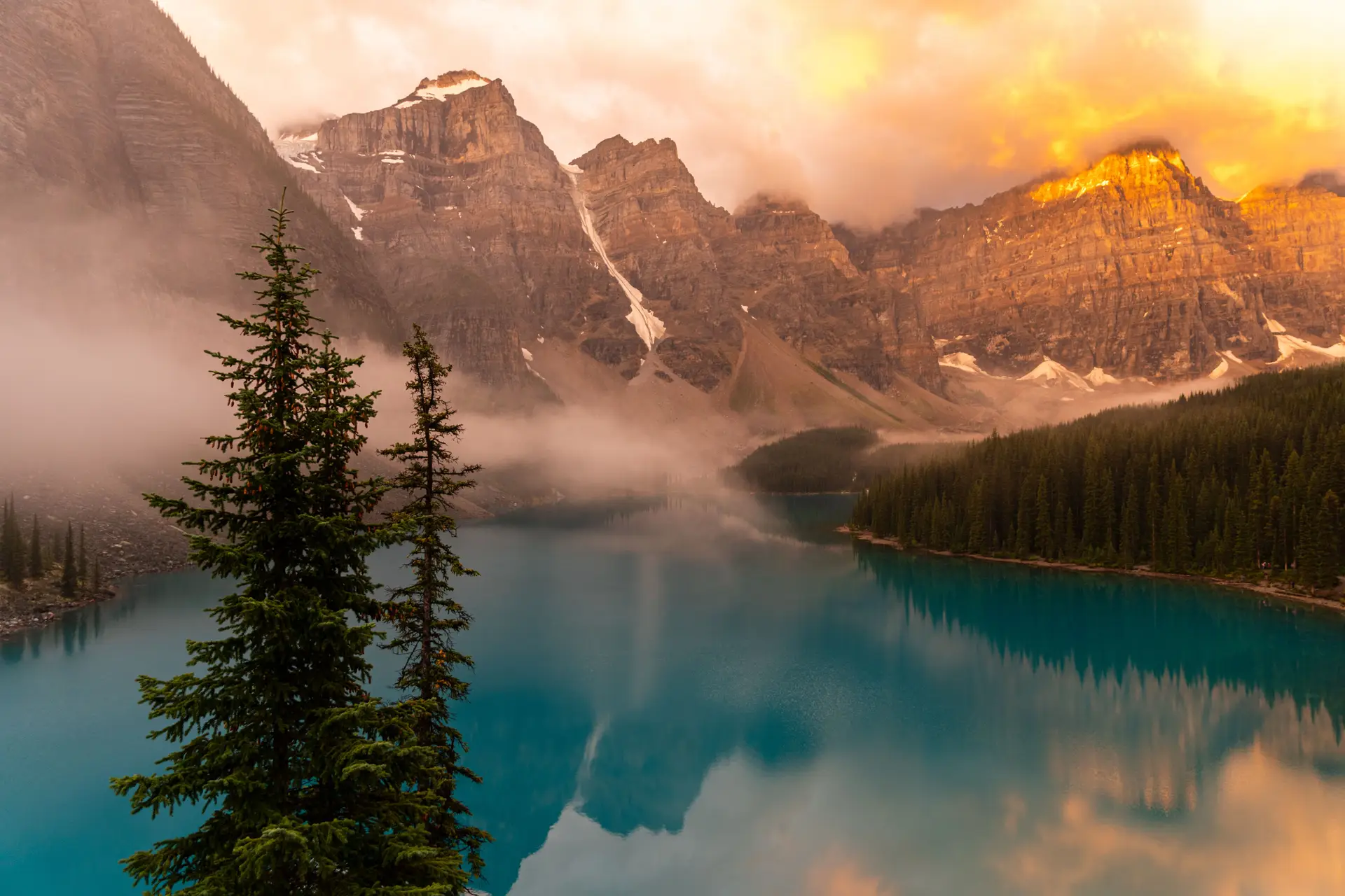 Misty sunrise over Moraine Lake with Canadian Rocky Mountains reflecting in turquoise waters